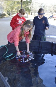 Regents School fourth-graders Olivia Mogridge (left), James Leister and Natalie Prather test their model ROV in a vat of water at the school. Photo by Michelle Edwards