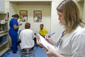 Kayla Carr (right), nurse practitioner, charts while third-year medical student Kristen Dent (left) helps nurse practitioner Kathy Rhodes examine 13-year-old Antavious Singleton at the Mercy Delta Express Project’s clinic at South Delta Middle School.