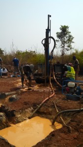 Workers drill a borehole with a rig and drilling mud as Zack Lepchitz and Dillon Hall examine soil cuttings.