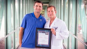 Hunter Patterson (left), a rising high-school senior who has already been admitted to UM, joins his father, Dr. Steven Patterson, in accepting a plaque honoring his recent donation, which coincidentally became the UM Foundation's millionth receipt.