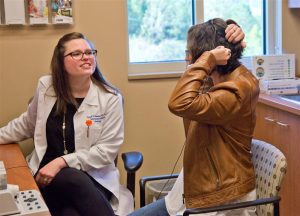Dr. Vicki Gonzalez, left, observes as Edmonson demonstrates positioning her cochlear implant.