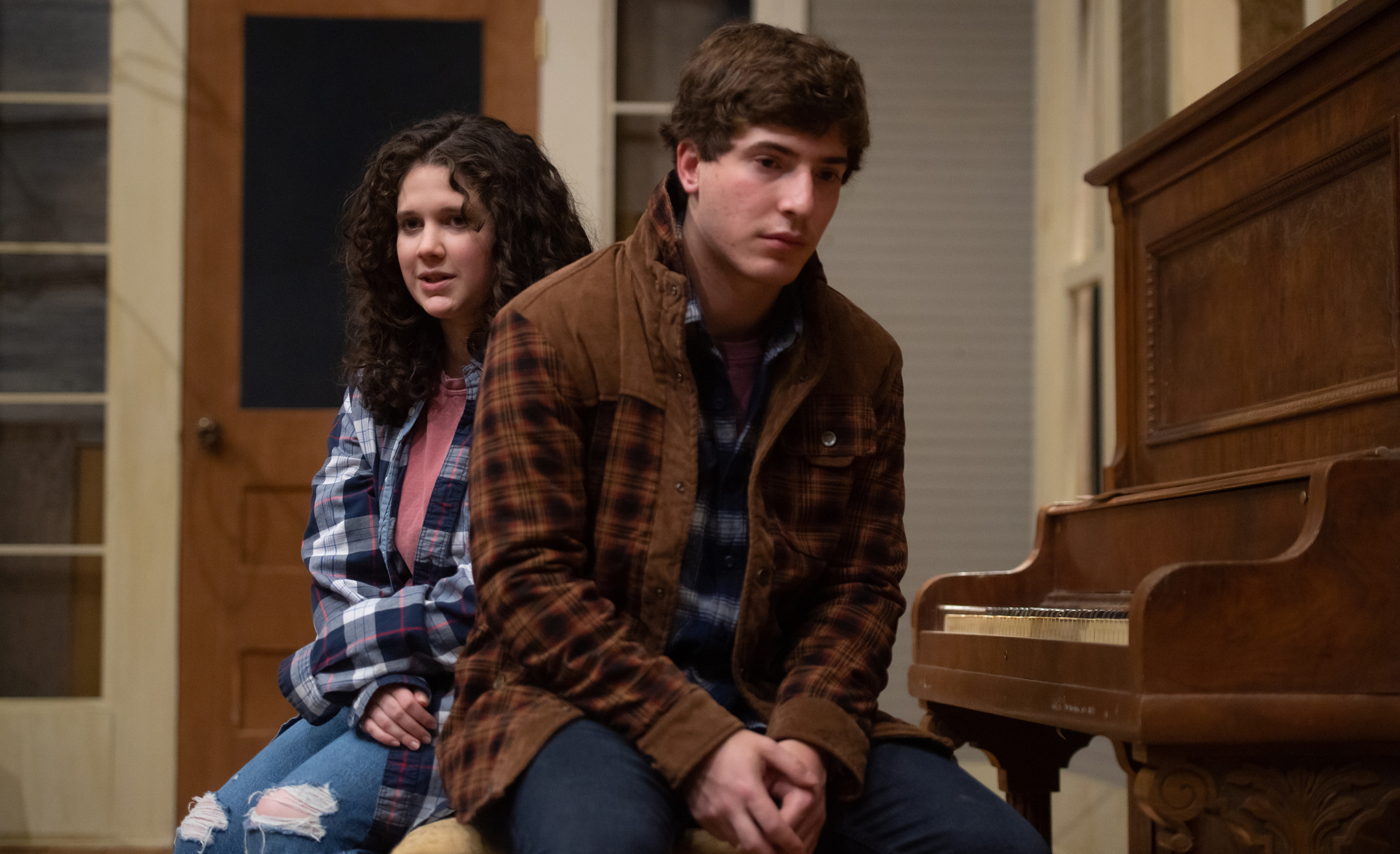 Madeline Colombo and Maxwell Glasser sit on a piano bench together while performing a scene in the play 'Hazel'