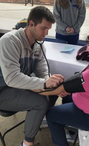 John White conducts blood pressure screening on an individual 