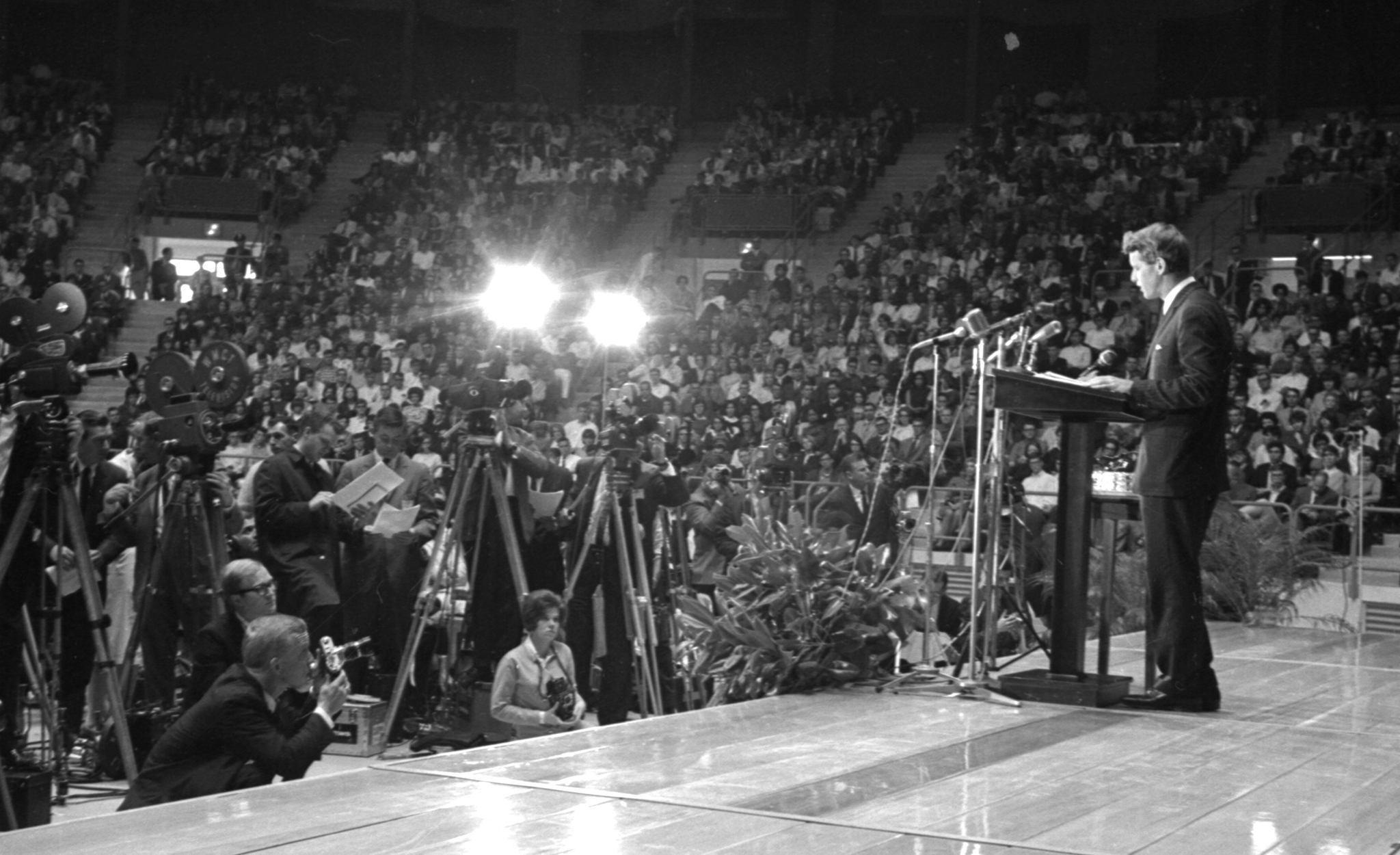 Black and white photo of Bobby Kennedy standing at podium addressing crowd in Tad Smith Auditorium.