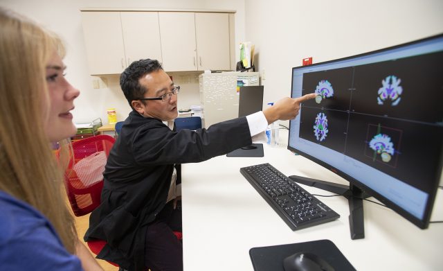 Nicole Jones (left) and communication sciences professor Tossi Ikuta go over brain scans at the South Oxford Center.
