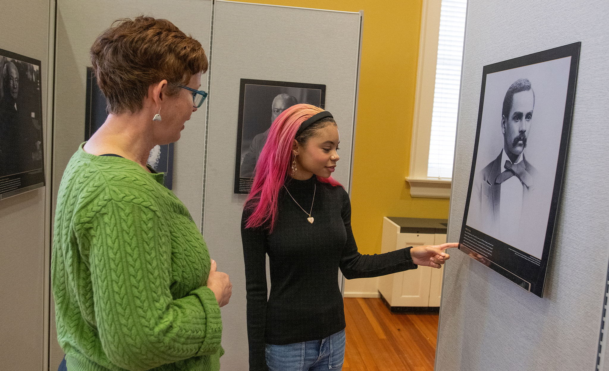 Molly Pasco-Pranger (left), chair and professor of classics, discusses the ’14 Black Classicists’ traveling exhibition on display at Bryant Hall’s Farrington Gallery with Kristen Randle, a sophomore classics major who helped install the exhibit. Photo by Thomas Graning/Ole Miss Digital Imaging Services