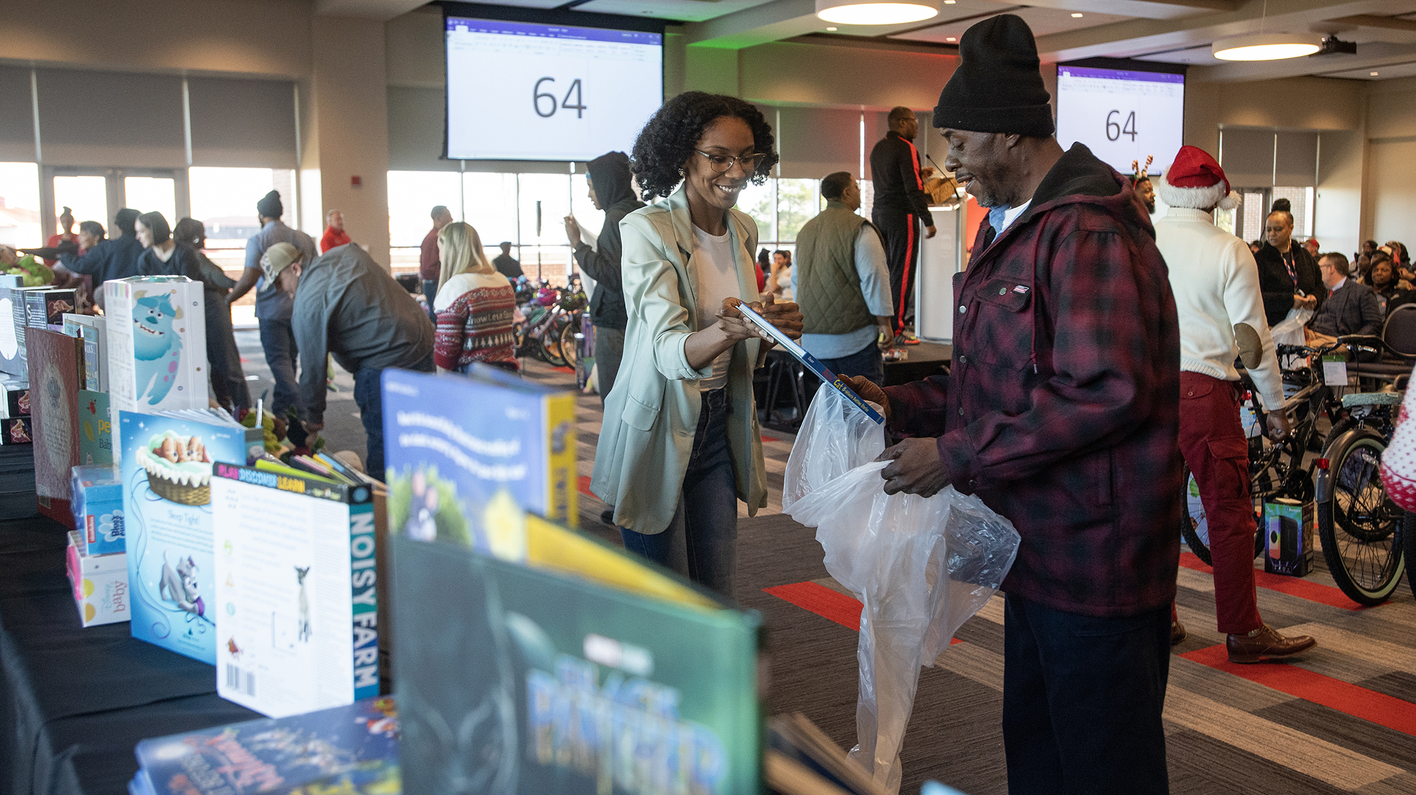 A representative of the UM Black Faculty and Staff Organization (left) helps a Facilities Management Department employee select gifts for his families at the annual Books and Bears distribution. Photo by Thomas Graning/Ole Miss Digital Imaging Services