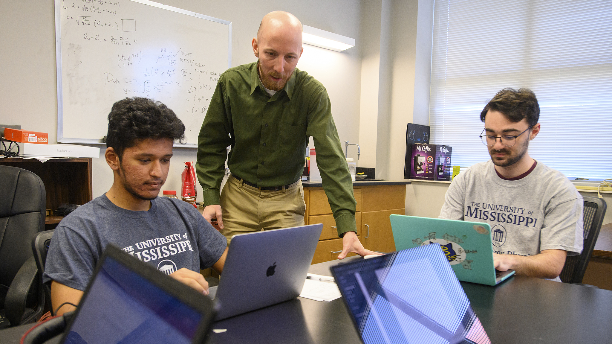 Jake Bennett (center), an assistant professor in the Department of Physics and Astronomy, reviews data with undergraduate physics majors Sakul Mahat (left) and Paul Gebeline. Bennett is part of an international group studying subatomic particles called charmed baryons, and their latest results have been published in the journal Physical Review Letters. Photo by Thomas Graning/Ole Miss Digital Imaging Services