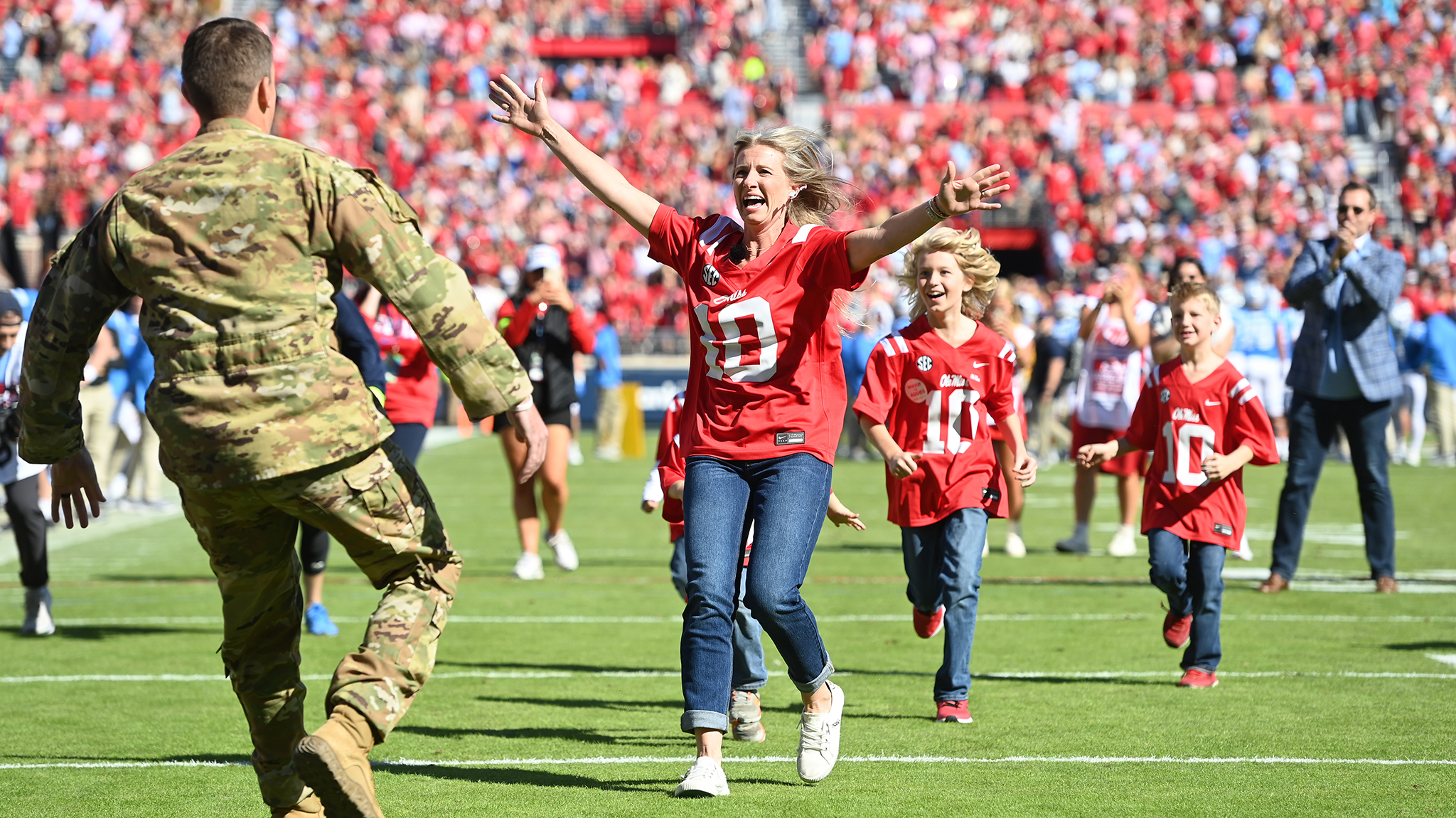 Elizabeth Rodgers (front) runs into the arms of her husband, Kyle Rodgers, at a surprise reunion during the first half of the Ole Miss-Texas A&M football game Saturday (Nov. 4). Kyle Rodgers returned from a 10-month deployment with the Army National Guard to reunite with his family as a part of Ole Miss Wish, a philanthropic effort of the University of Mississippi Office of Veteran and Military Services that seeks to give military families memorable experiences. Photo by Thomas Graning/Ole Miss Digital Imaging Services