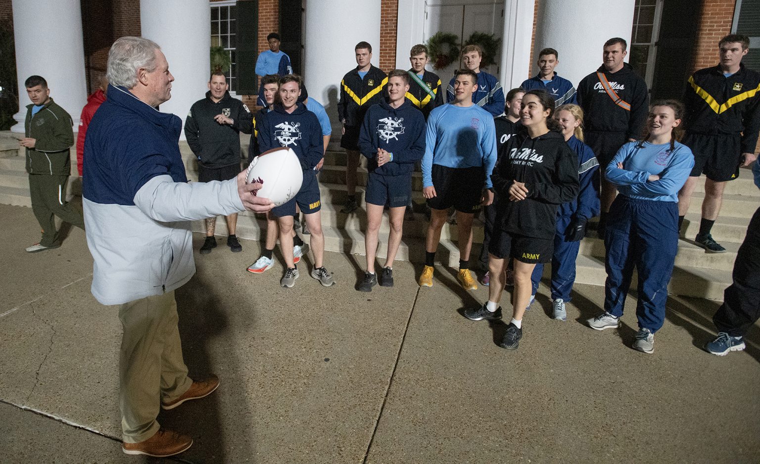 Chancellor Glenn Boyce (left) accepts the game ball from Ole Miss Magnolia Battalion cadets after the 2022 Egg Bowl Run. Each year, cadets from Ole Miss and Mississippi State University leg the game ball nearly 100 miles across north Mississippi. Photo by Thomas Graning/Ole Miss Digital Imaging Services
